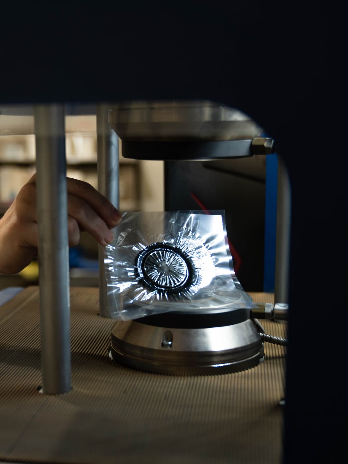 A technician holding a rubber test specimen under a materials testing rig in the RDL lab